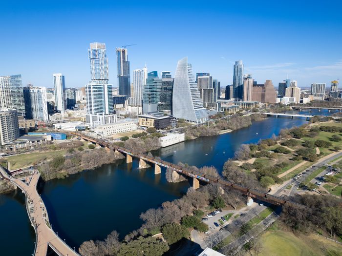 Aerial view of Austin, Texas skyline with landmarks including river and footbridge.