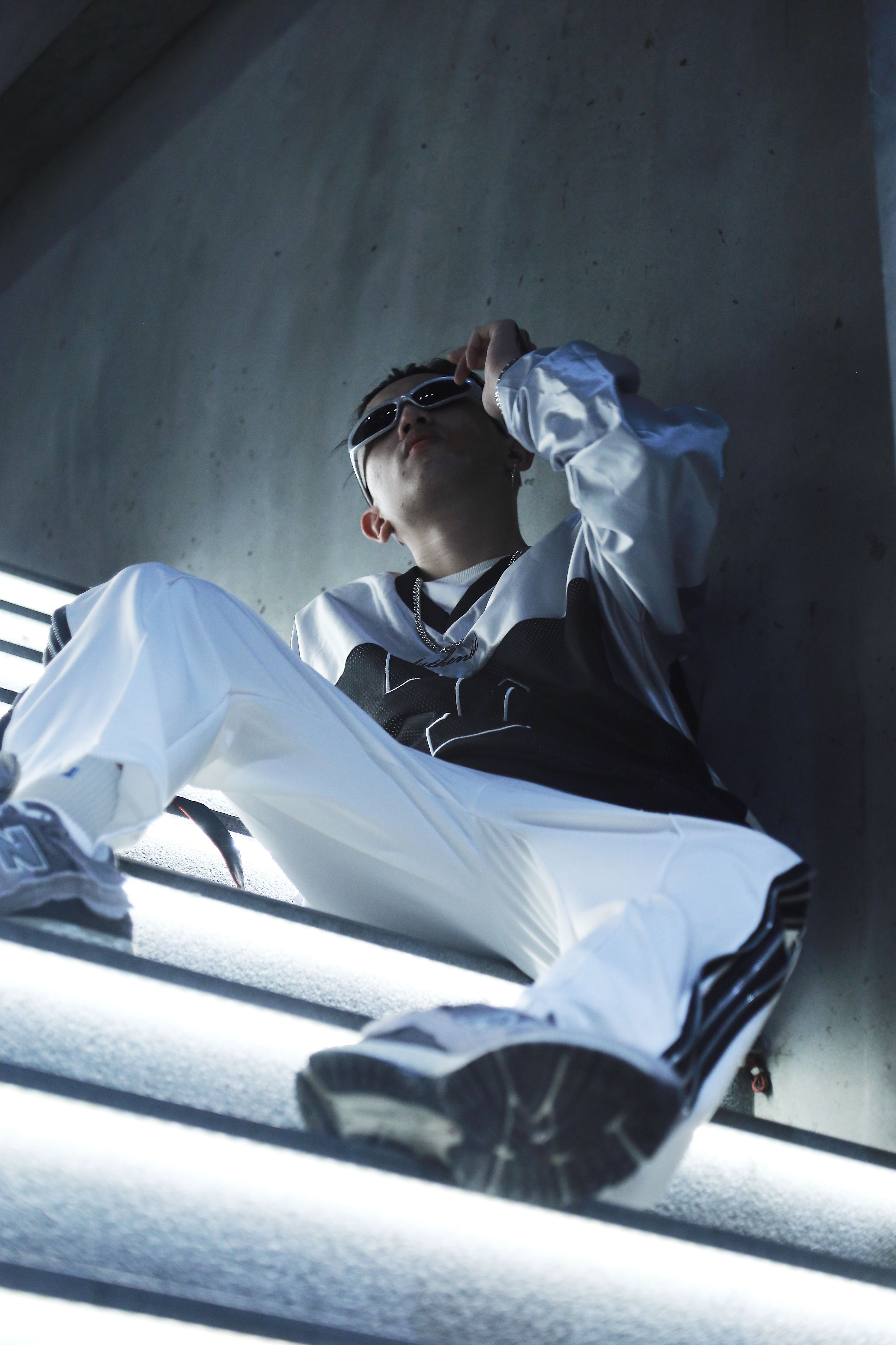 Stylish model in a tracksuit posing on glowing stairs in an urban setting.