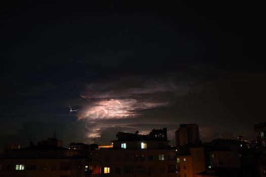 A striking image of a thunderstorm illuminating the city skyline at night.
