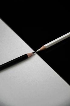 Artistic composition of black and white pencils on contrasting backgrounds.