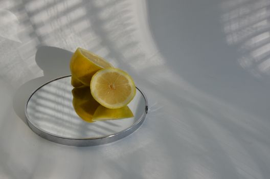 Sliced lemons on a mirror casting shadows, showcasing minimalistic food photography.