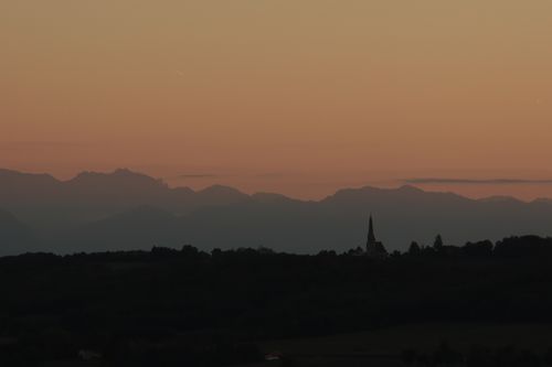 Free A tranquil sunset scene with silhouetted mountains and a distant spire captured at dusk. Stock Photo