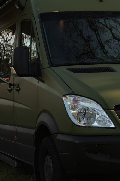 A green van parked in the grass next to a tree · Free Stock Photo