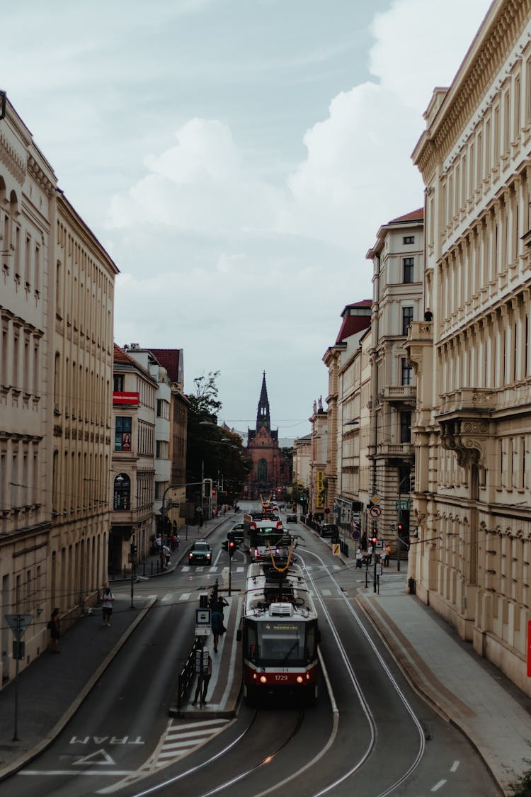 Tram Riding On A Street In Brno With Jan Amos Comenius Church In The Distance