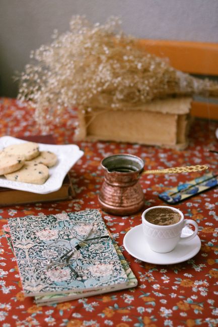 A warm scene with coffee, cookies, and a Turkish pot on a patterned tablecloth.