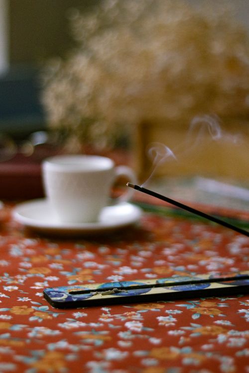 Free A calming scene with incense smoke and a coffee cup on a floral tablecloth. Stock Photo