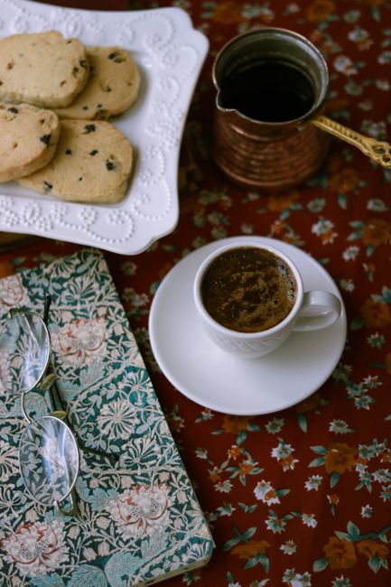 A warm, inviting still life with coffee, cookies, and floral patterns.