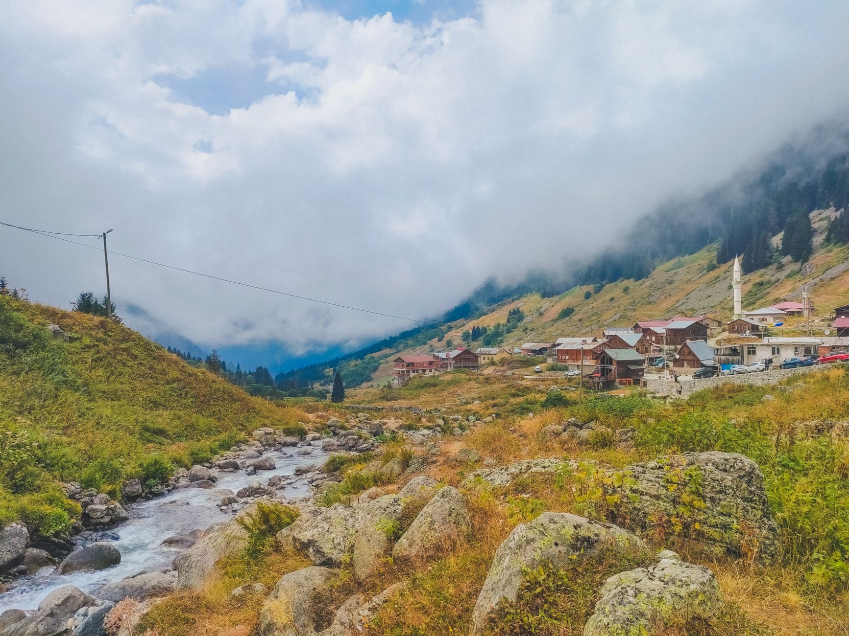 Stone houses with wooden balconies stacked above a mountain stream