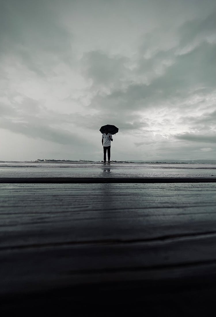 Man With Umbrella On Sea Shore