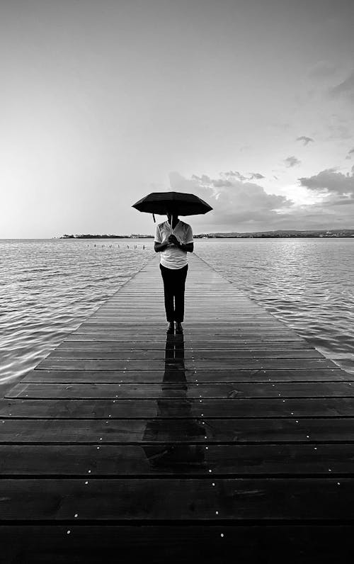 Man Standing with Umbrella on Pier in Black and White