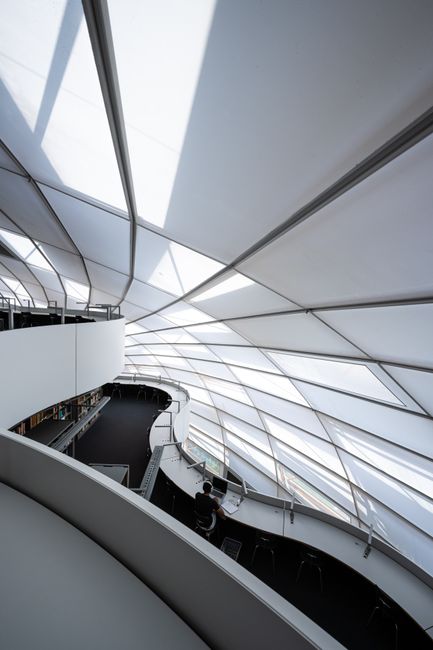 A modern library with a unique glass ceiling, ideal for students studying under natural light.