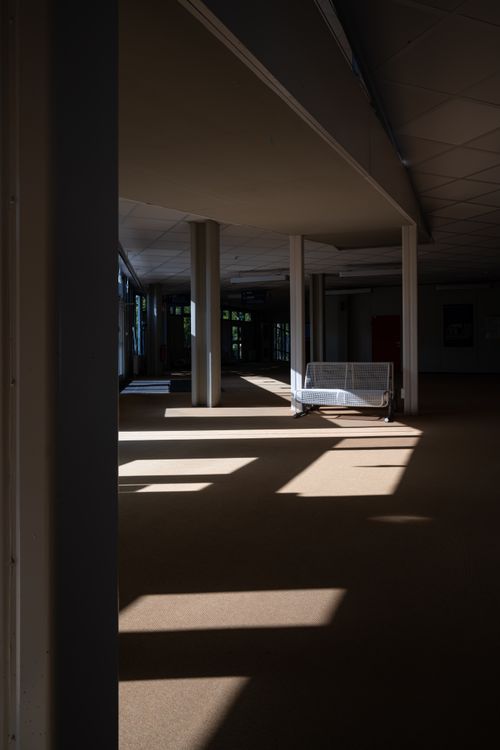Free Spacious corridor with sunlit shadows casting across an empty interior space. Stock Photo