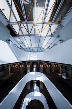 A contemporary library interior with natural light and geometric patterns from a skylight.