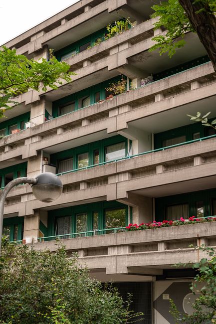 Urban apartment with green balconies and lush foliage in a city setting.