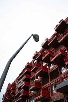 Low angle view of a modern building with red balconies against a clear sky.