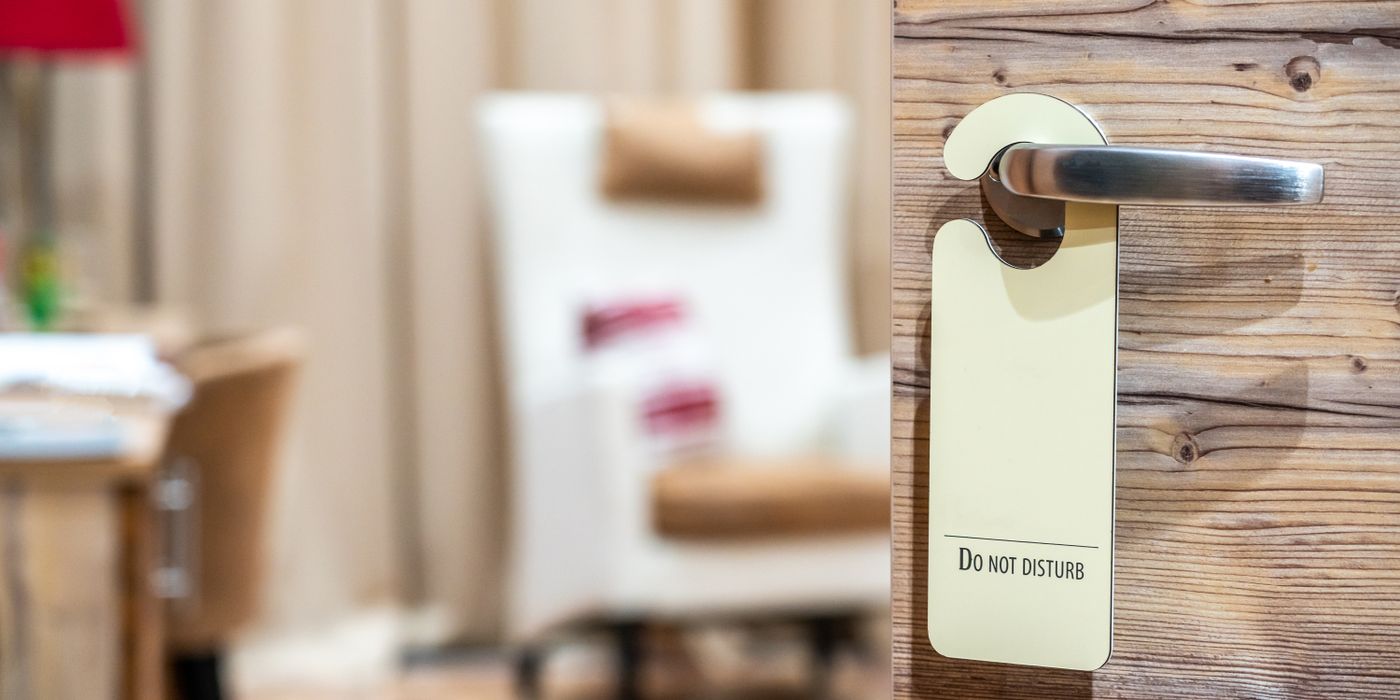 Hotel room door with a Do Not Disturb sign hanging on the handle