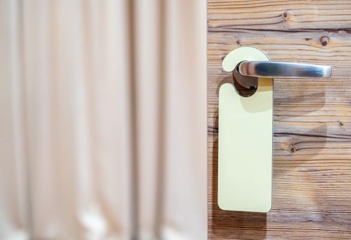 Elegant wooden door with a stainless steel handle and hotel tag.