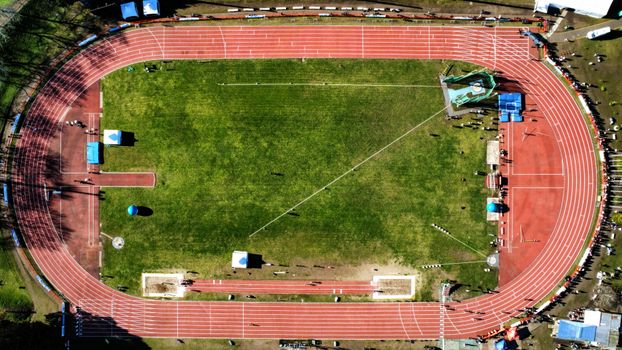 Drone shot of an athletics stadium with red tracks and green field in Mar del Plata, Argentina.
