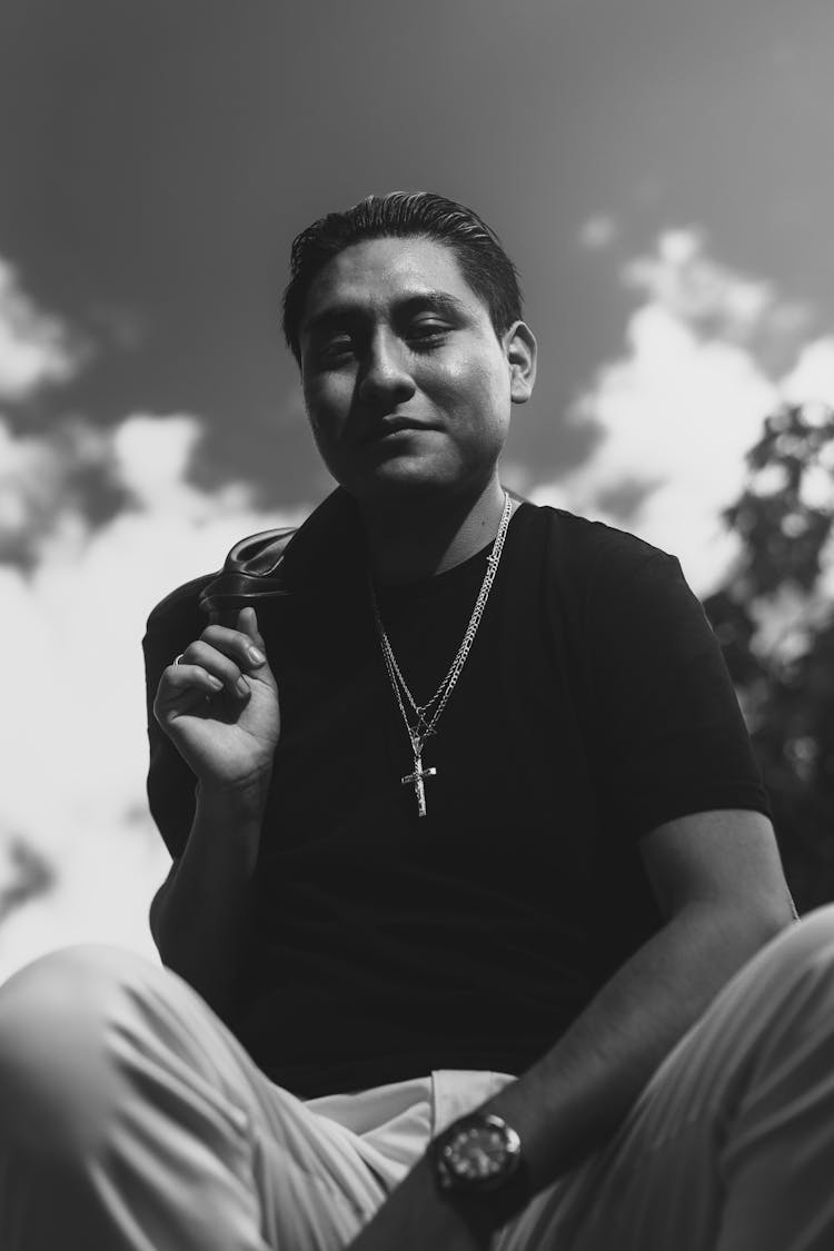 Black And White Photo Of A Man Sitting Outside 