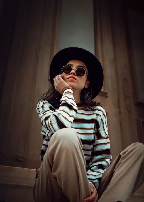 Free Portrait of a fashionable woman wearing sunglasses and hat, sitting outdoors in Istanbul. Stock Photo