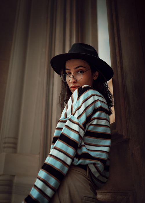 Free A fashionable woman poses in a striped sweater and hat, showcasing modern style. Stock Photo