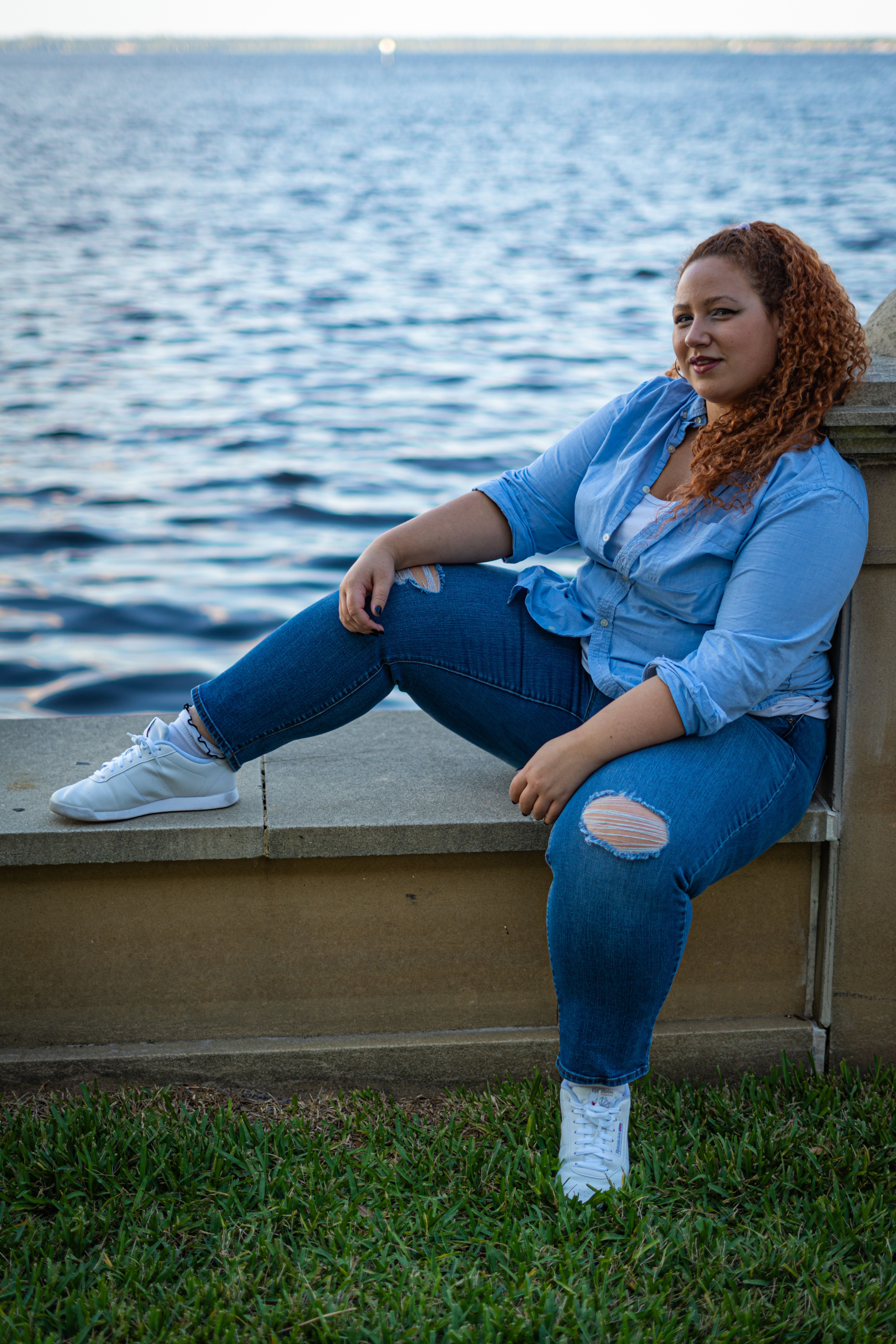 Woman in Blue Shirt Sitting and Posing on Wall · Free Stock Photo