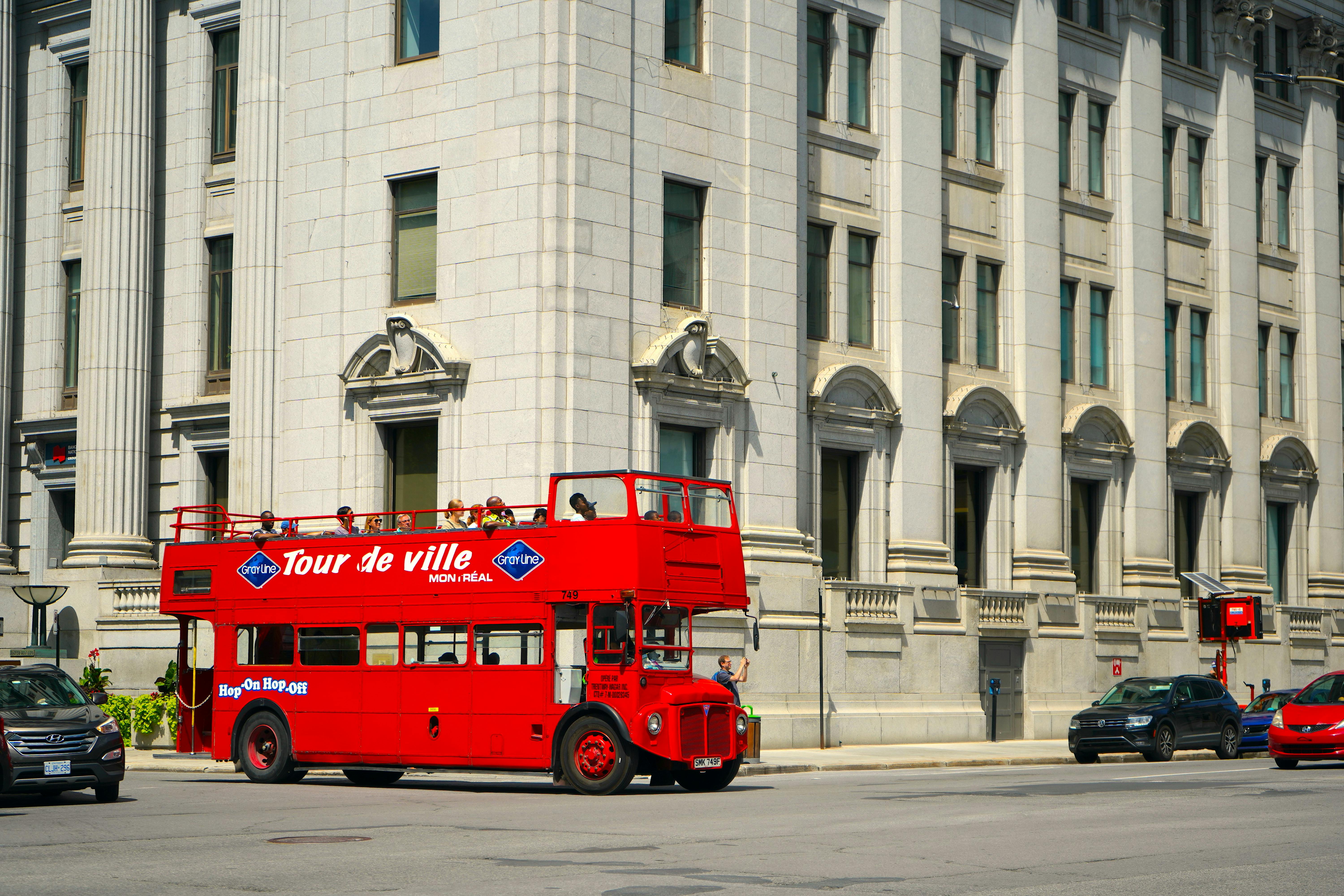Red double-decker tour bus on city street in Montreal, Canada with historic architecture. - Montreal
