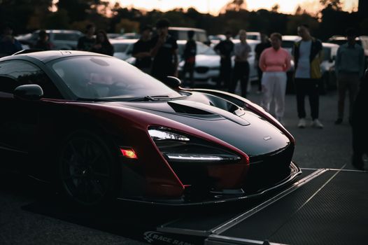 A sleek sports car showcased surrounded by a crowd during an evening event.