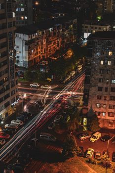 Dynamic night aerial shot of a bustling city crossroads with light trails from cars.