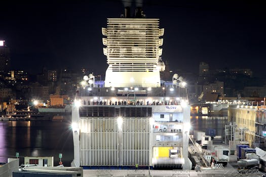 Ferry docked at night in Genoa, Italy. Illuminated urban skyline in background.