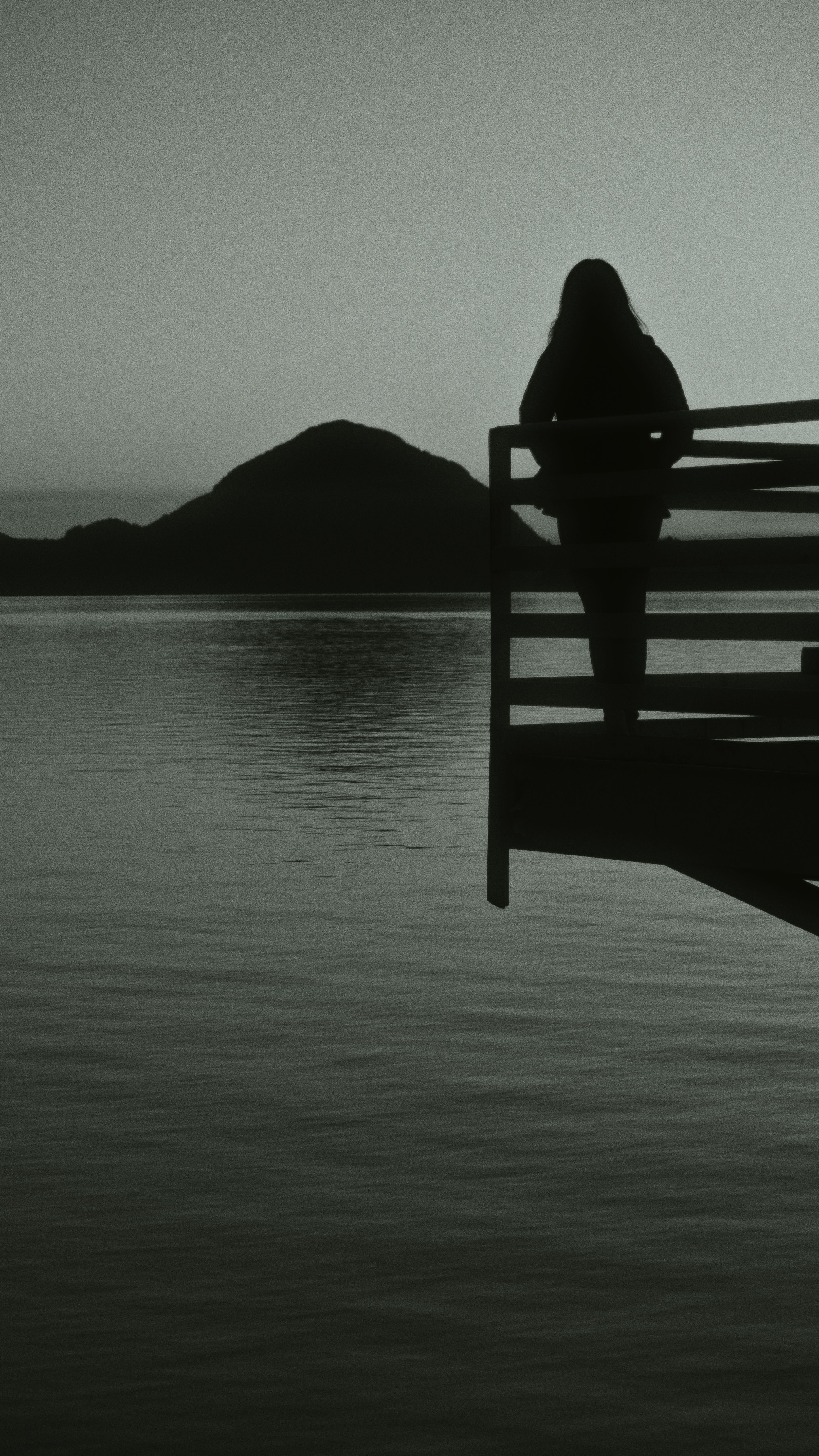 A woman standing on a dock looking out at the water · Free Stock Photo