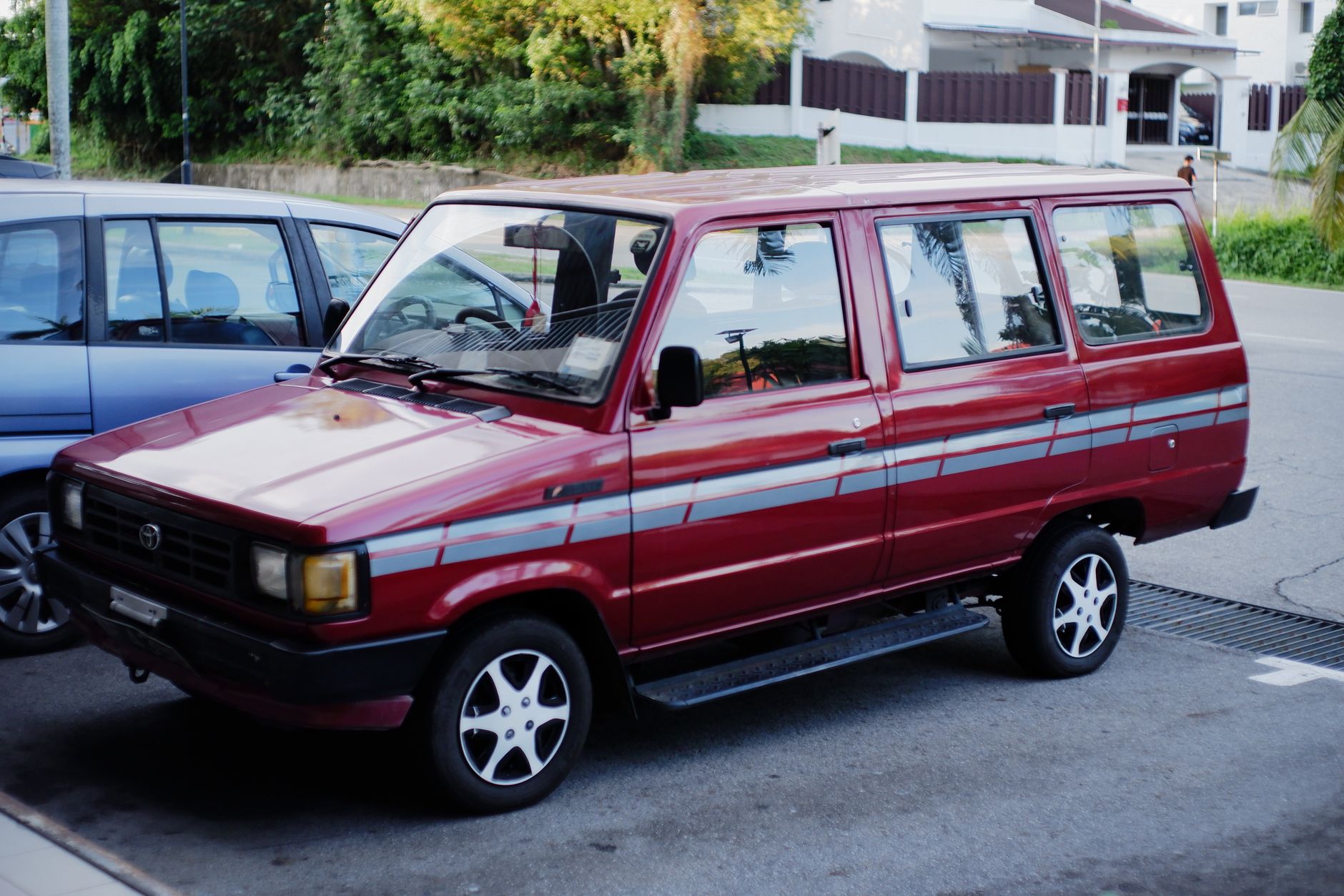 A vintage red minivan parked outdoors in Bandar Seri Begawan, Brunei.