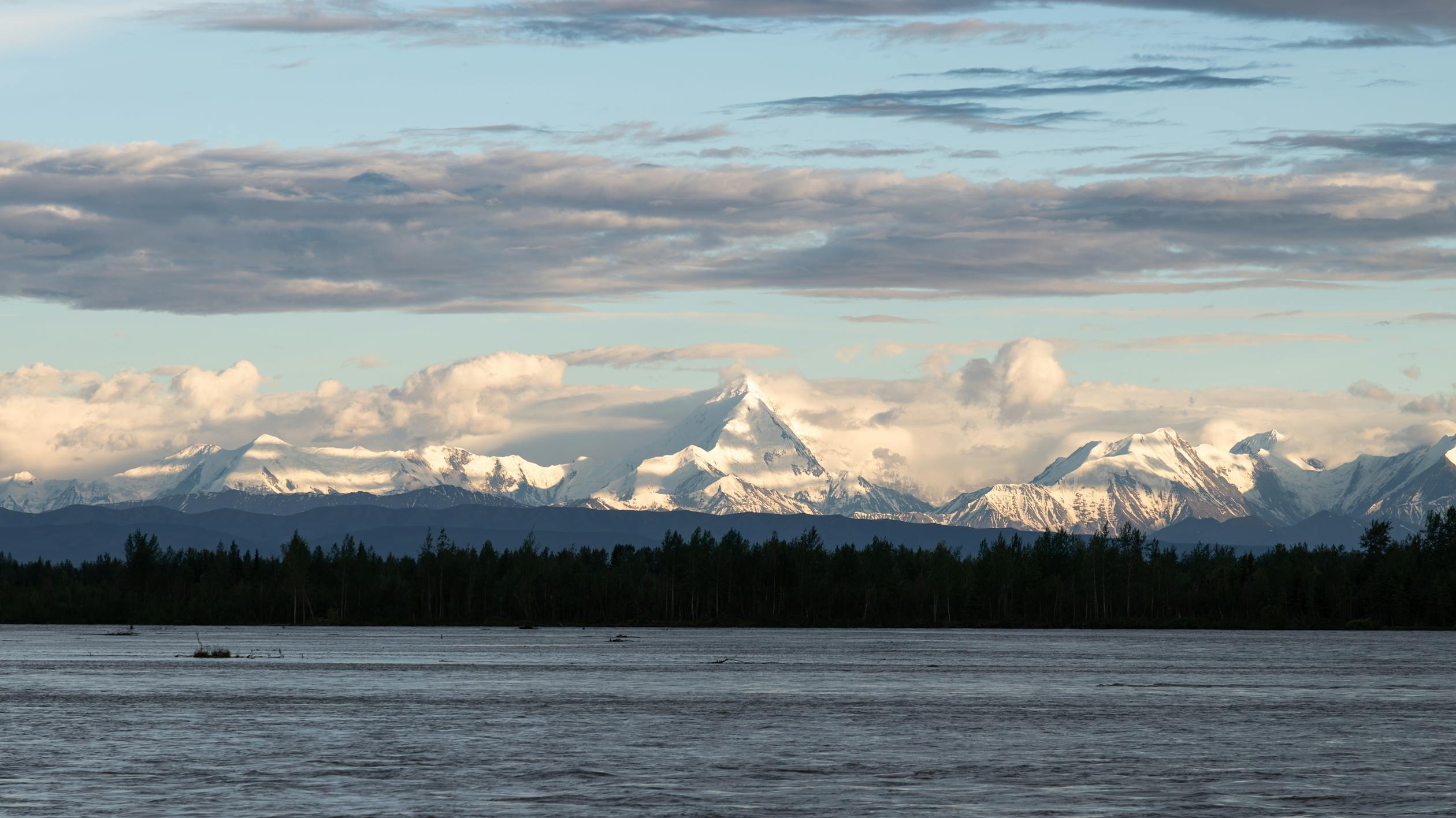 A boat is floating on the water with mountains in the background