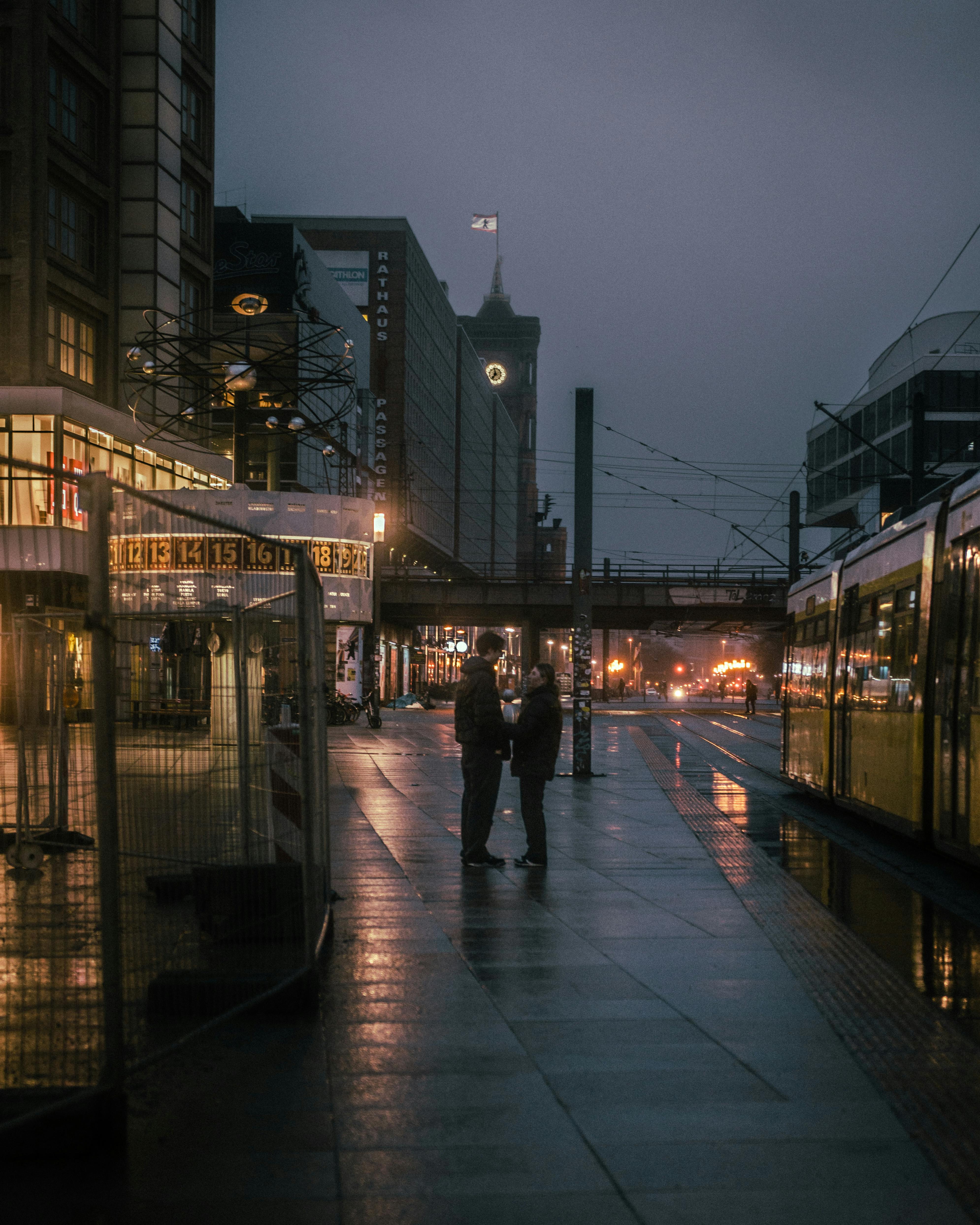 Moody evening street scene in Berlin featuring modern architecture, trams, and pedestrians.