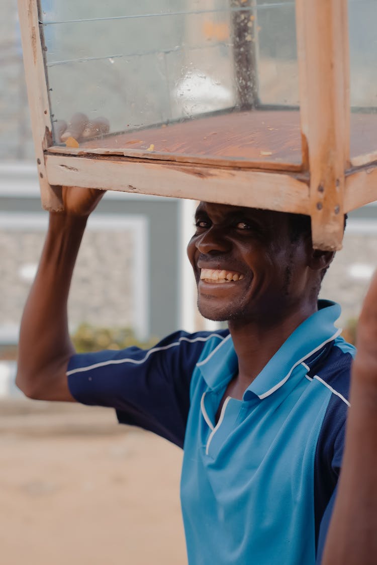 Smiling Black Man Carrying Stool On Head