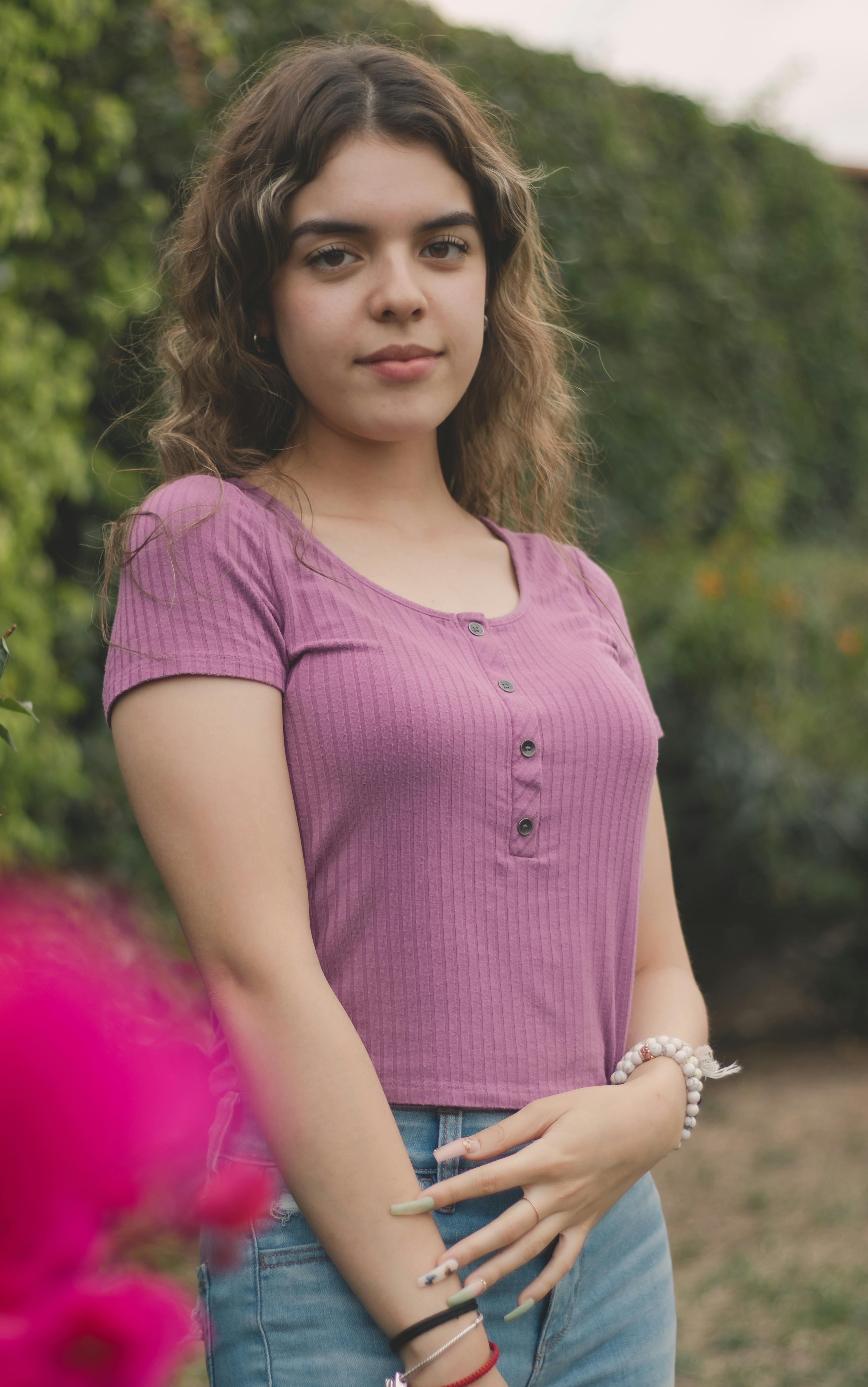 A young woman poses outdoors, showcasing fashion in natural light.
