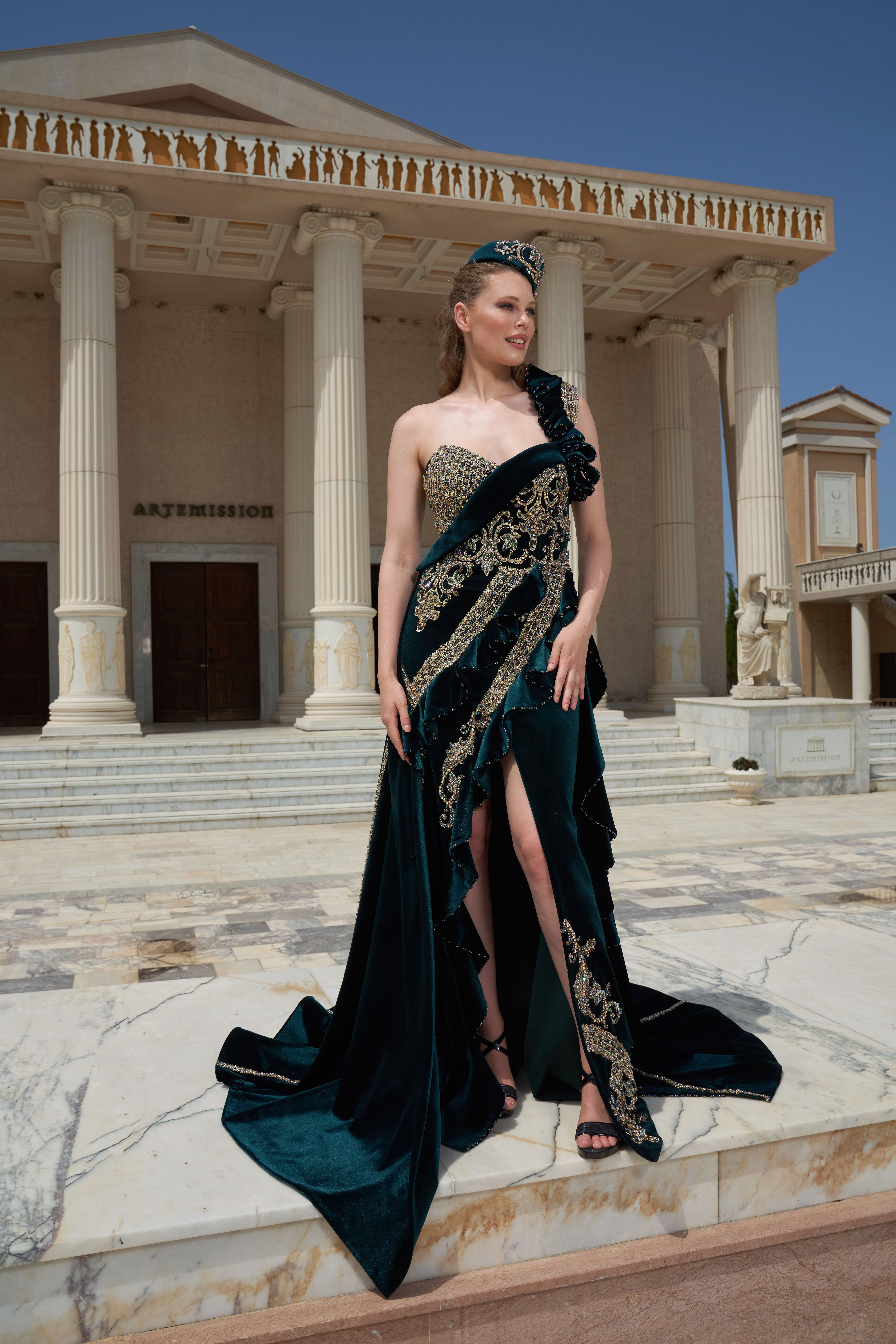 A model in a sophisticated dress stands before classic columns in İzmir, showcasing elegance and style.