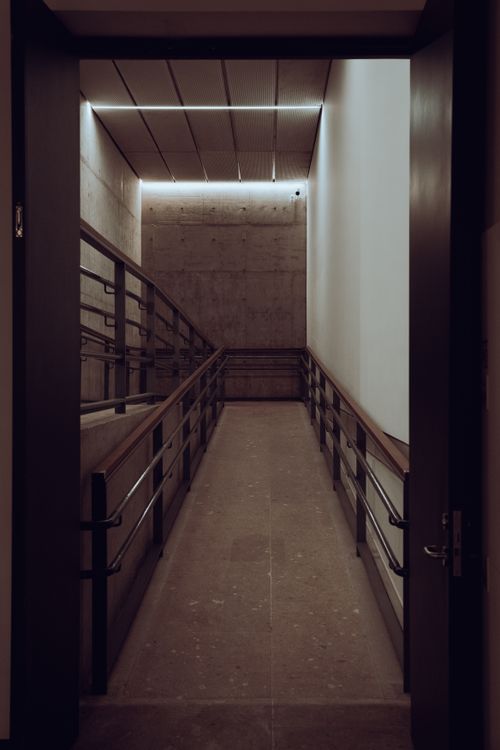 Free A sleek and minimalist indoor corridor with industrial handrails and subtle lighting. Stock Photo
