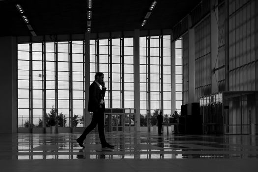 Silhouette of a businessman walking in a modern glass building lobby.