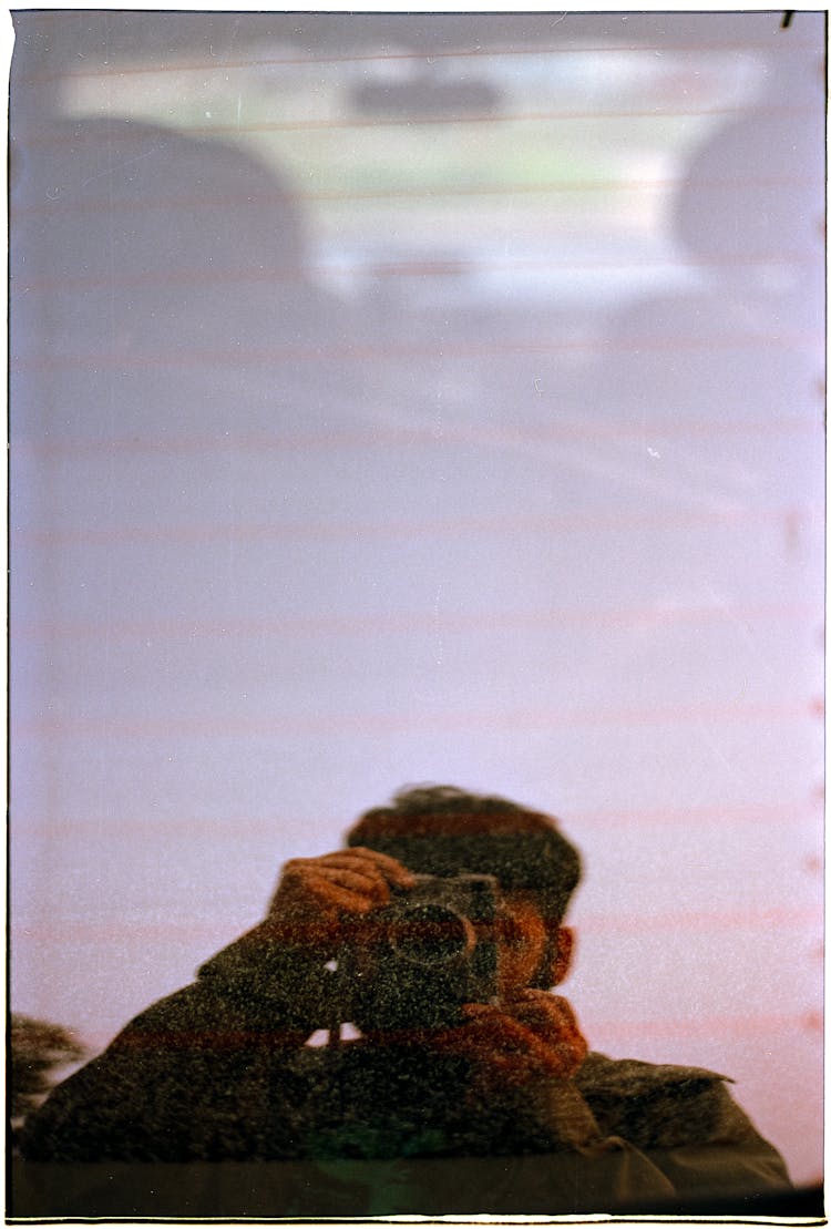 Man With Camera Reflecting In Rear Windscreen