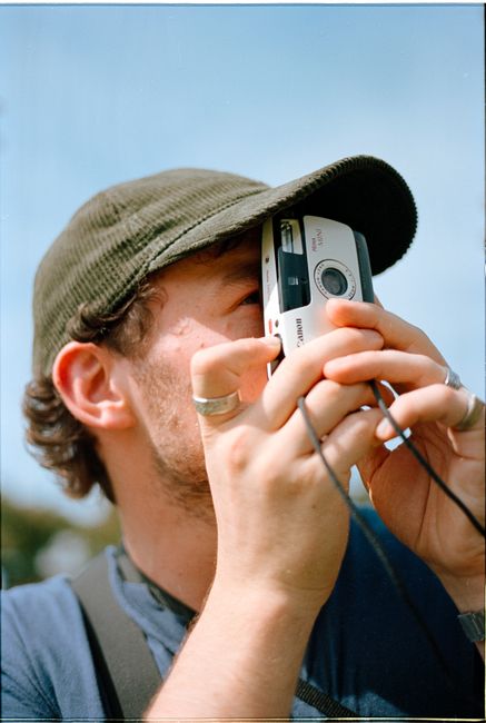 A young man with a camera capturing outdoor moments on a sunny day.