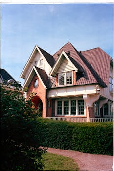 Beautiful facade of a suburban two-story house with greenery and clear sky.