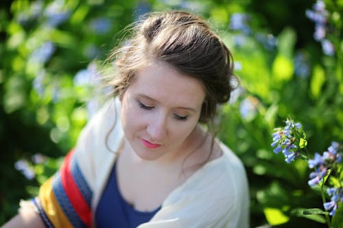 Fotografia Di Messa A Fuoco Selettiva Di Donna Accanto A Fiori Con Petali Blu