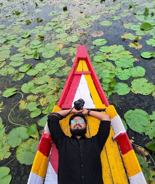 Man in Shirt Lying Down on Boat on Lake