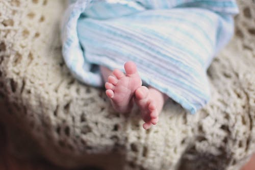 一條藍色毯子下面的嬰兒腳