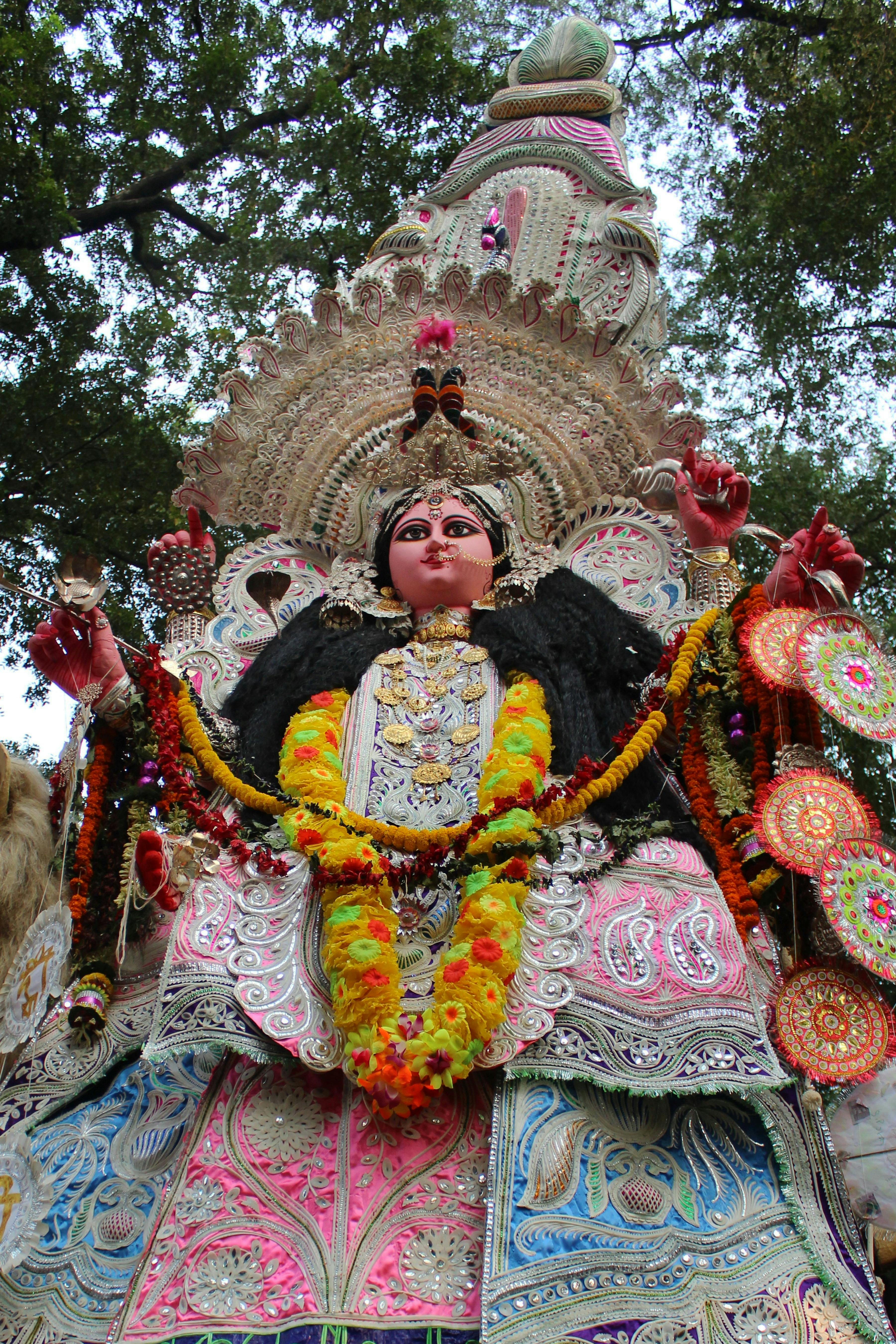 Intricate statue of a Hindu goddess adorned with vibrant flowers, showcasing spiritual artistry.