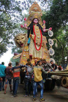 A vibrant street celebration of Jagaddhatri Puja with a large goddess statue.