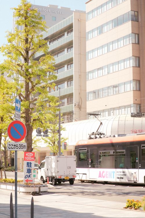 Free A city street scene with tram, buildings, and urban signage on a sunny day. Stock Photo