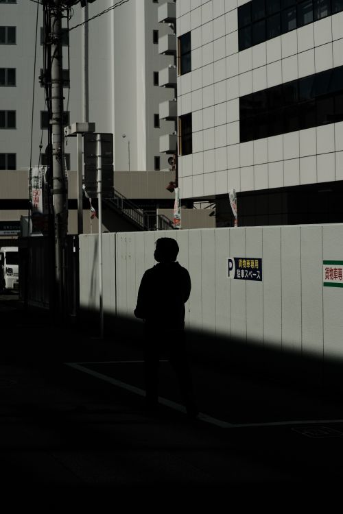 Free Silhouette of a lone pedestrian walking through urban cityscape in low light. Stock Photo