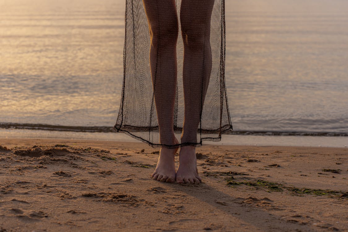 Close-up of a Woman Standing Barefoot on a Beach at Sunset